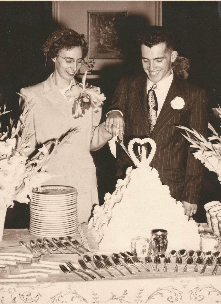 Couple Cutting Wedding Cake with a Cake topper on top