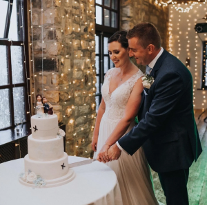 Wedding Couple Cutting Cake with a Cake Topper on Top