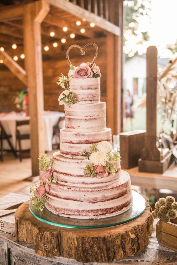 Naked cake with flowers and a heart-shaped wooden cake topper