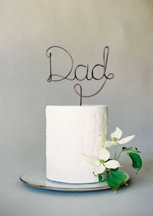 A simple wire cake topper that says 'Dad'